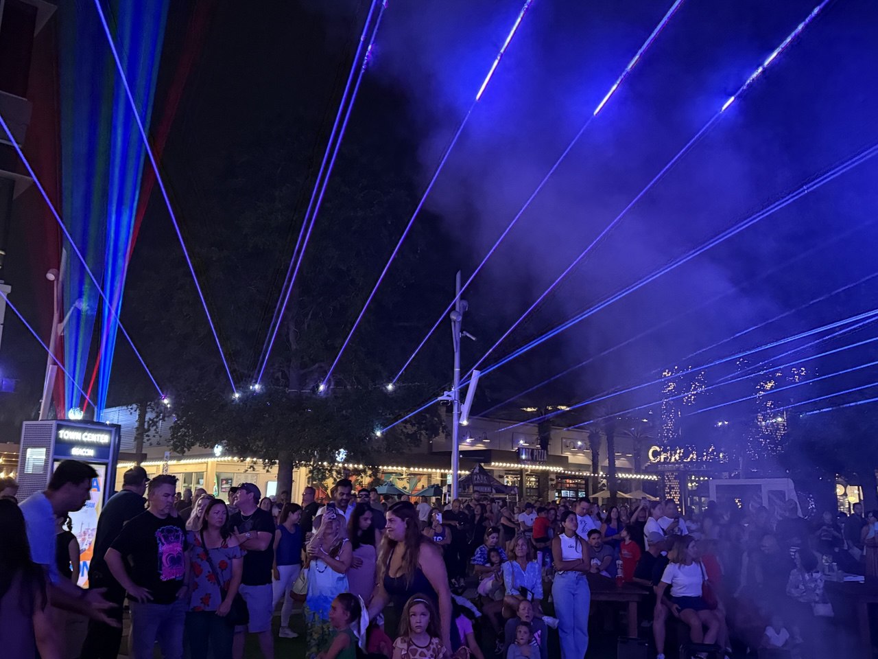 Blue and purple laser beams streaming over a packed crowd at Town Center