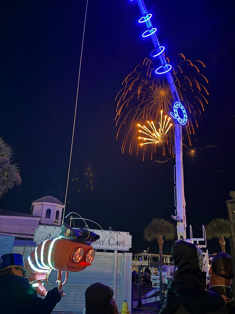 Shrimpy suspended from crane with golden fireworks cascading above the crowd
